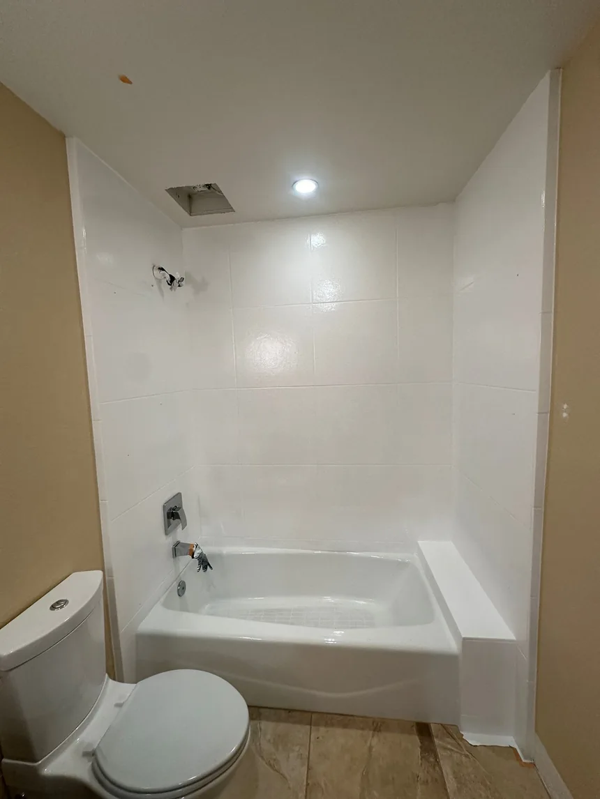 A shower alcove refinished in white, walls and tub together.