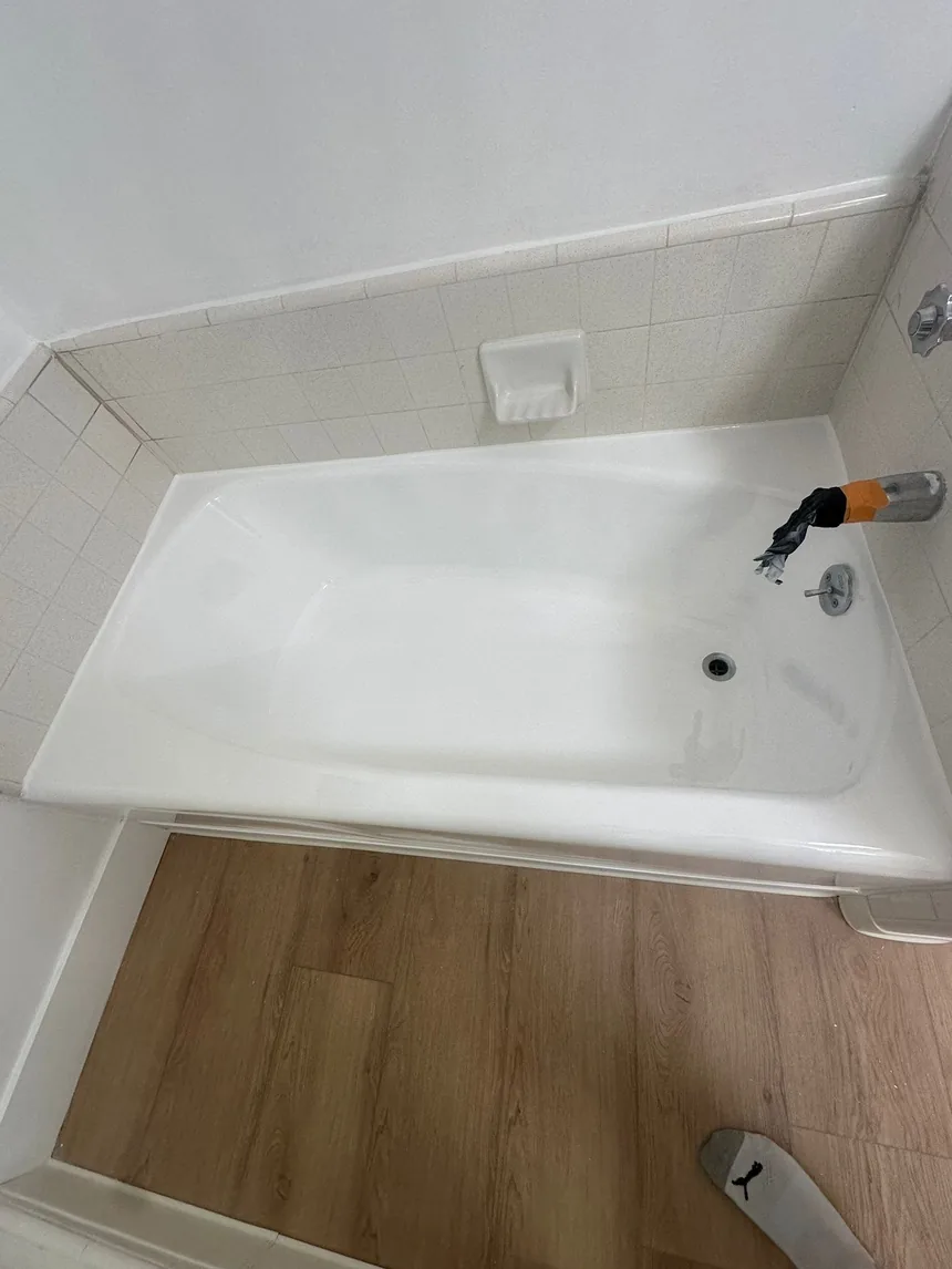 The same bathtub refinished, glossy white against the same white tile.
