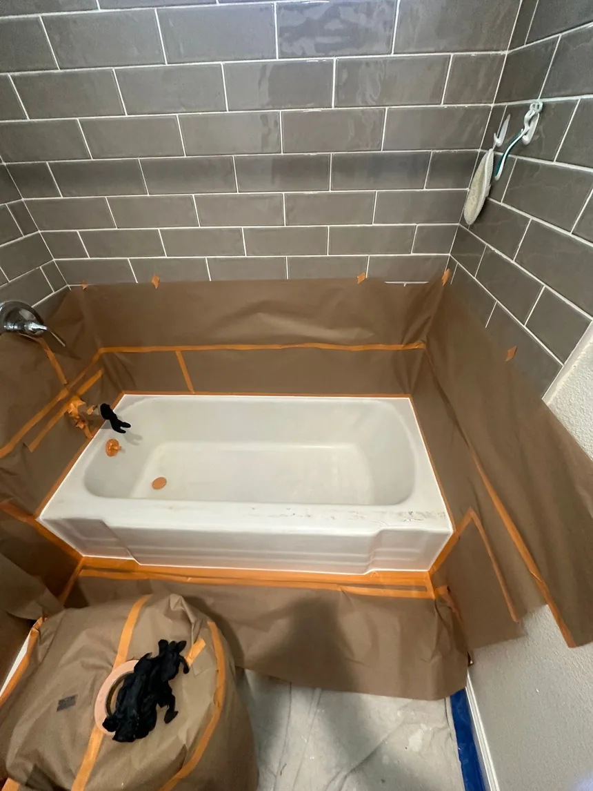 A bathroom masked off for spraying: paper and tape over the tile, the toilet bagged and the floor covered.