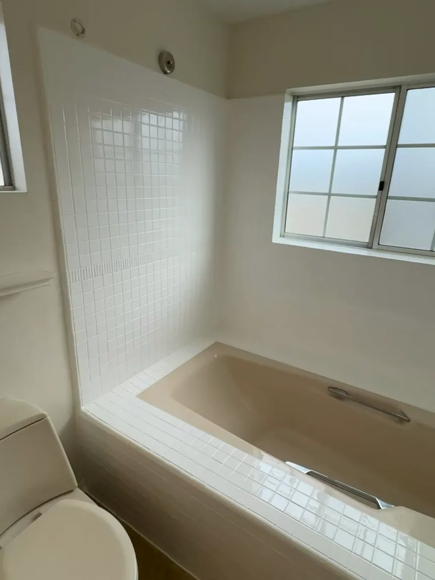 A bathroom with the tub, deck and surrounding tile refinished in white.