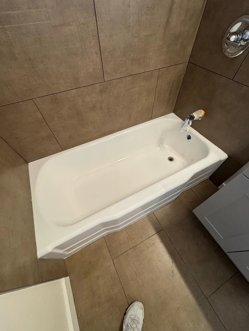 The same bathtub refinished in white against the same taupe tile.