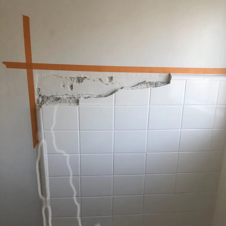 The same repair sanded level and masked off with tape, the tile edge straight again.