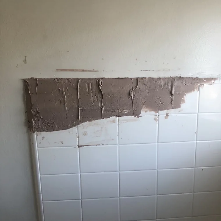 The same wall with fresh gray mortar troweled across the damaged area.
